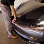 An employee closes the front hood of a Tesla Inc. Model 3 electric vehicle at the company's showroom in Newport Beach, California, U.S., on Friday, July 6, 2018.