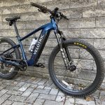 Image of a blue hard tail mountain bike leaning against a grey stone wall.