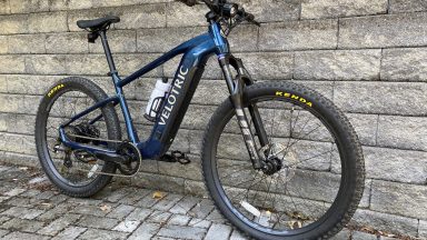 Image of a blue hard tail mountain bike leaning against a grey stone wall.