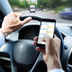 Close-up Of A Man's Hand Typing Text Message On Mobile Phone While Driving Car