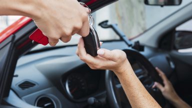 Salesman handling car keys to customer