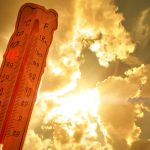 A warm orange sun partly obscured by clouds, with a distorted, melting thermometer in the foreground.