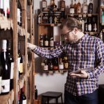 Man looking over the offerings at a wine store with a tablet in hand.