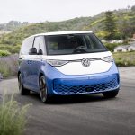 A white and blue VW ID Buzz drives along a road