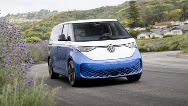 A white and blue VW ID Buzz drives along a road