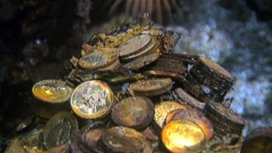 gold coins and gold bars scattered on the ocean floor