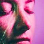 A stock photo illustration of a person's face lit with pink light.