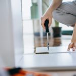 Cropped shot of young woman assembling furniture with a screwdriver. She is assembling a wooden cabinet in the living room in her new apartment