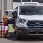 A woman loads things into the side of a Ford E-Transit that's been uplifted as a refrigerated van