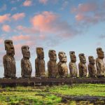 A row of grey rock sculptures of human torsos and heads, arranged in a long line.