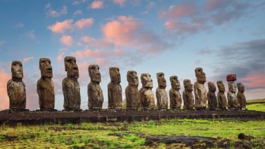 A row of grey rock sculptures of human torsos and heads, arranged in a long line.