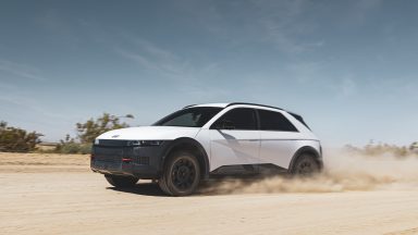 A white Hyundai Ioniq 5 XLT drives across the desert, kicking up sand