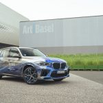 A BMW X5 has been wrapped by an artist and parked in front of a frosted glass building