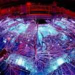 Image of a large, circular chamber covered filled with a lot of mechanical equipment, all of which is lit by blue internal glows and covered with massive, branching trails of lightning.