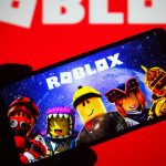 Someone holding up a smartphone with "Roblox" on the screen.