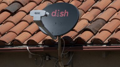 A satellite TV dish with the Dish logo on a roof.