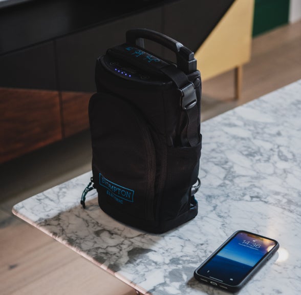 The Brompton Electric battery next to a smartphone on a coffeetable