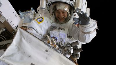 October 18, 2019. NASA astronaut Jessica Meir waves at the camera during a spacewalk with fellow NASA astronaut Christina Koch (out of frame). They ventured into the vacuum of space for seven hours and 17 minutes to swap a failed battery charge-discharge unit (BCDU) with a spare during the first all-woman spacewalk. The BCDU regulates the charge to the batteries that collect and distribute solar power to the orbiting lab's systems.