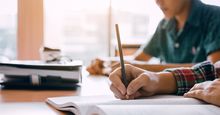 Close up of students hands writing in notebooks. Homework study school classroom high school