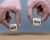 Hands are holding two cubes with the words "sell" and "buy". 