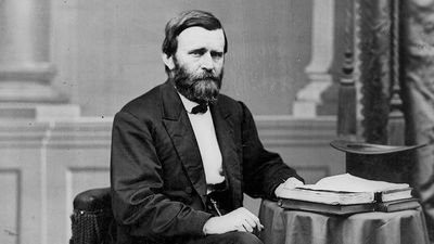 Full-length portrait of Ulysses S. Grant seated at table with books and top hat, facing right, ca. 1869-1877.