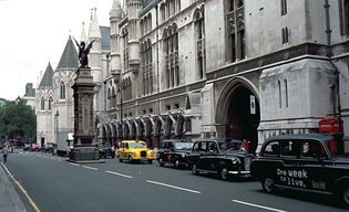 The Strand and the south facade of the Royal Courts of Justice, London. The griffin-topped Temple Bar, which marks the boundary between Westminster and the City of London, was erected in the 1670s to replace the 14th-century Temple Bar gatehouse.