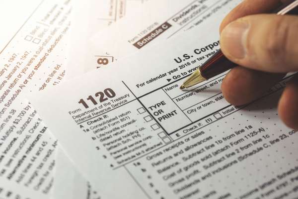 Close up of a hand filling out a corporate income tax form. Form 1120 IRA. Department of the Treasury Internal Revenue Service