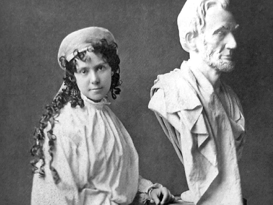 American sculptor Vinnie Ream (1847-1914) and her bust of Abraham Lincoln on the stand used in the White House while President Lincoln posed for her. Photo taken between 1865 and 1870. Her full sized Lincoln See Asset: 182233