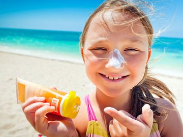 girl applying sunscreen at the beach