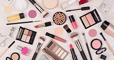 Makeup cosmetics such as eyeshadows, lipstick, mascara and makeup accessories on white, wooden background, top view