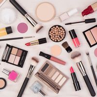 Makeup cosmetics such as eyeshadows, lipstick, mascara and makeup accessories on white, wooden background, top view