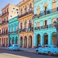 Vintage taxis on street against historic buildings, Cuba, Havana. Vintage cars parked on roadside. Taxis on street in city. Vehicles against residential buildings.