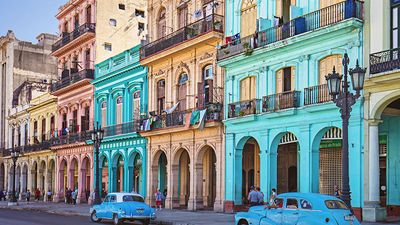 Vintage taxis on street against historic buildings, Cuba, Havana. Vintage cars parked on roadside. Taxis on street in city. Vehicles against residential buildings.