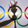 Silhouette of hand holding sport torch behind the rings of an Olympic flag, Rio de Janeiro, Brazil; February 3, 2015.