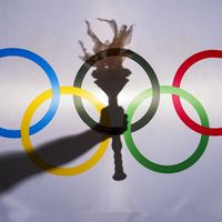 Silhouette of hand holding sport torch behind the rings of an Olympic flag, Rio de Janeiro, Brazil; February 3, 2015.