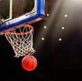 A ball swishes through the net at a basketball game in a professional arena.