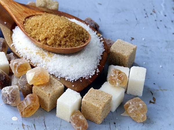 Various types of sugar. Organic compound. Glucose. Refined sugar, raw sugar, brown sugar, sugar cubes spoon wood