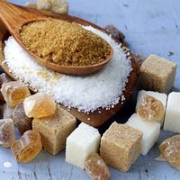 Various types of sugar. Organic compound. Glucose. Refined sugar, raw sugar, brown sugar, sugar cubes spoon wood