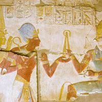 Ancient Egyptian carving of Pharaoh Seti I holding his flail before the god of the underworld Osiris with Horus behind him. Abydos Temple, Egypt. Ancient carving, on public display for 2,000 years