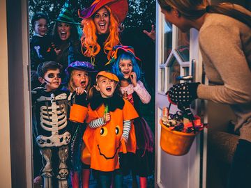 Group of children and their parents playing trick or treat on Halloween.