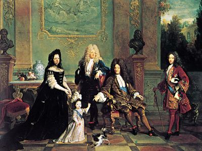 French dress of the Louis XIV period: male attire of long coat with wide, turned-back sleeves, waistcoat, lace cravat, tight-fitting breeches, and periwig. Louis XIV and His Family, oil painting by Nicolas de Largillière, 1711; in the Wallace Collection, London.