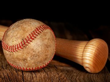 An old worn baseball and wood bat