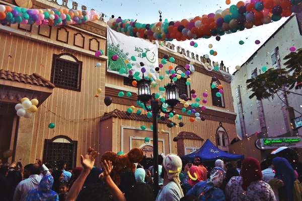 Young men throw balloons and glitter from above the mosque at the celebration Eid Al-Fitr after prayers playing with balloons outside of Al-seddeeq mosque, Al-Mansourah, Egypt. 17 July 2015.