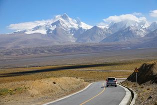 A vehicle driving along the base of the Himalayas, Tibet Autonomous Region, China.