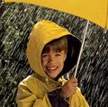 rain. Child in the rain, wearing a rain coat, under a yellow umbrella. April Showers weather climate rain storm water drops