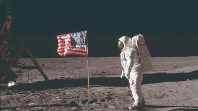 (Buzz Aldrin) stands next to the U.S. flag at Tranquility Base on the Moon during NASA's Apollo 11 mission, July 20, 1969. Aldrin's forward-leaning stance was the normal resting position of an astronaut wearing the life-support pack.