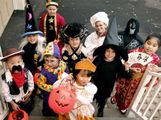 Children dressed in halloween costumes and masks. Group of trick or treaters standing on steps in their Halloween costumes. Holiday