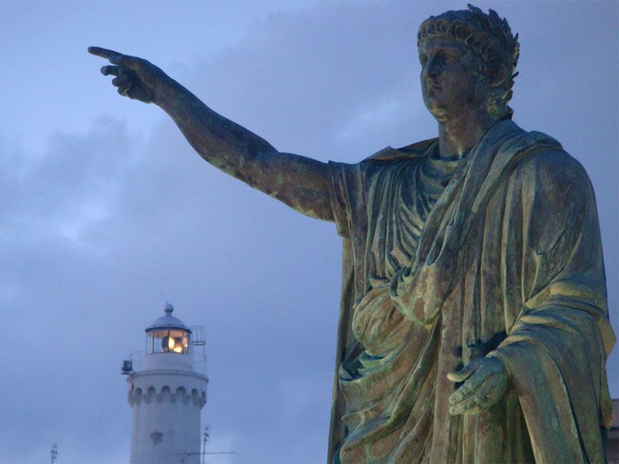 Statue of of the Roman emperor Nero with the lighthouse in the background at Anzio, Lazio region, Italy