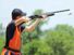 Young man skeet shooting with airborne shell