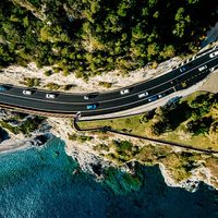 Aerial view of road going along the mountain and ocean or sea. Drone photography from above